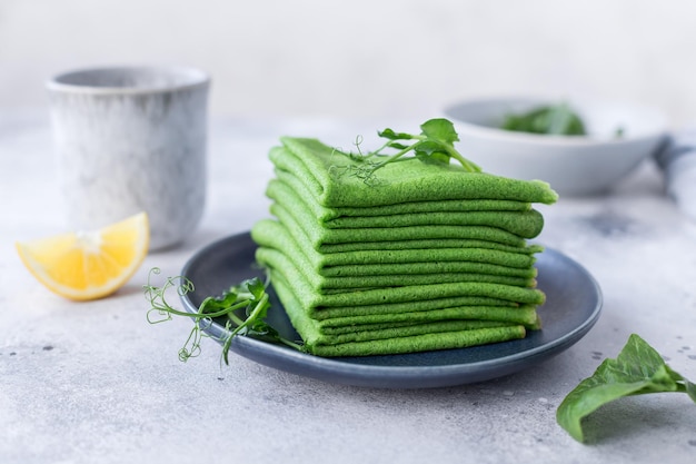 Stack of green spinach pancakes crepes with herbs