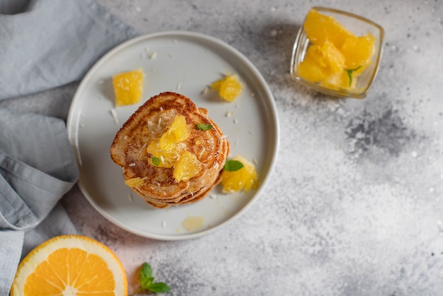 Stack of homemade pancakes with orange and mint healthy breakfast gray concrete surface,