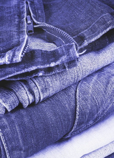 A stack of jeans tinted in the trendy color of 2022 by very peri