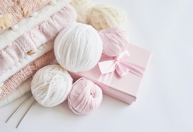 Stack of knitted clothes and balls of yarn knitting needles accessories for knitting Baby clothes Needlework hobby knitting handwork