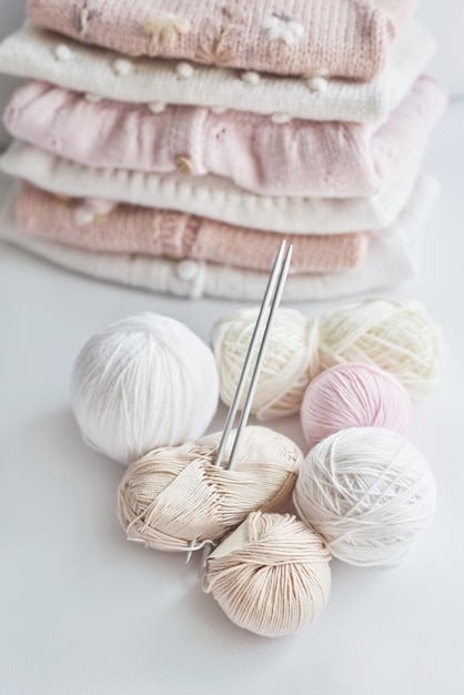 Stack of knitted clothes and balls of yarn knitting needles accessories for knitting Baby clothes Needlework hobby knitting handwork