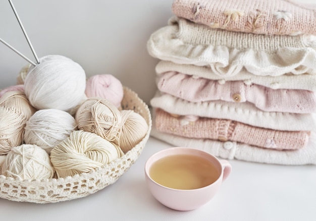 Stack of knitted clothes and balls of yarn knitting needles accessories for knitting Baby clothes Needlework hobby knitting handwork