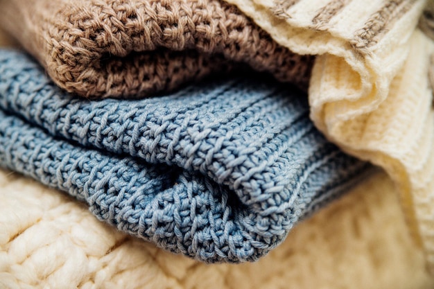 A stack of knitted clothes in different colors Texture and background Crocheting is a hobby and a pleasant leisure Closeup of stitches and threads