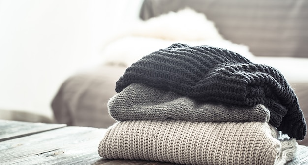 A stack of knitted sweaters on a wooden table