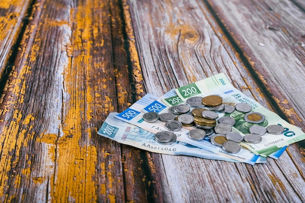 Stack of Mexican coins and bills on wooden table