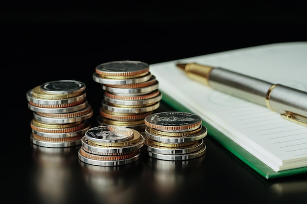 Stack of money coin with notebook and pen, concept marketing finance business background and coins.