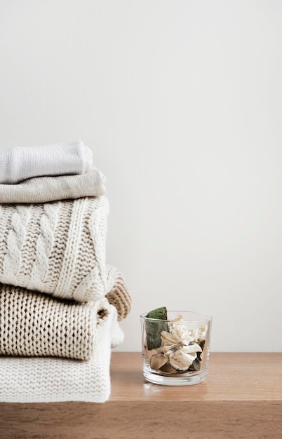 A stack of neatly folded warm knitwear wool on a wooden shelf and a beige background