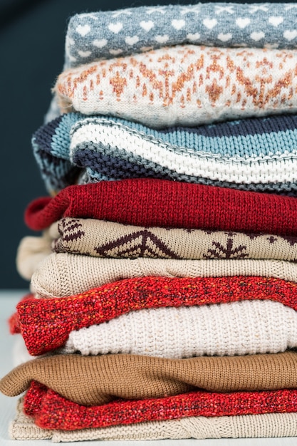 Stack of new woolen and cotton sweaters and jumpers prepared for cold autumn and winter days