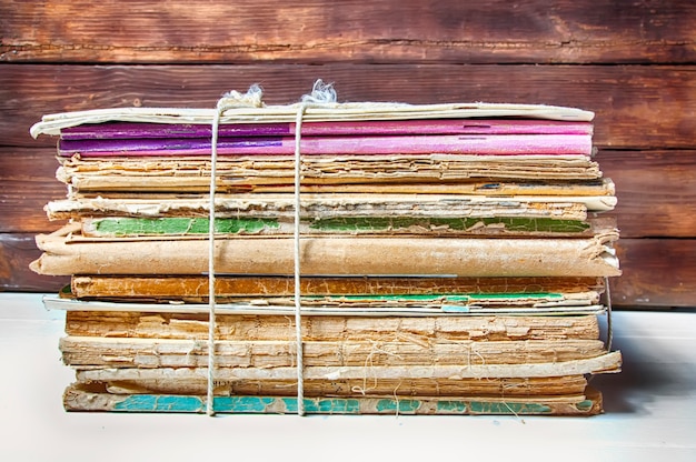 A stack of old books and magazines tied with rope on a white table