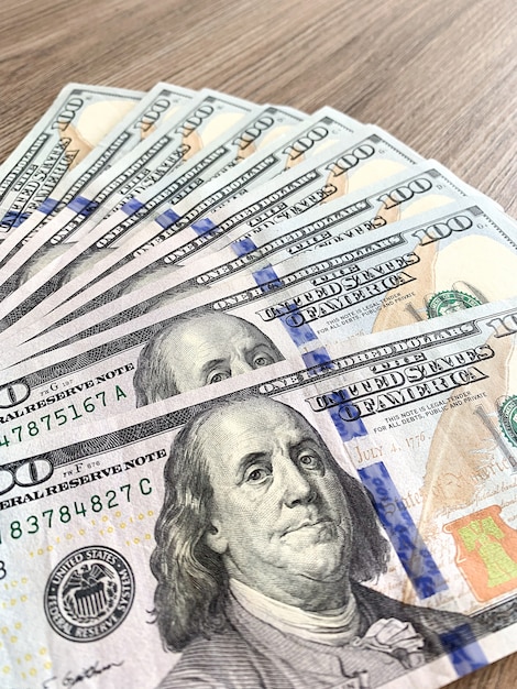 Stack of one hundred dollars bills on wooden desk