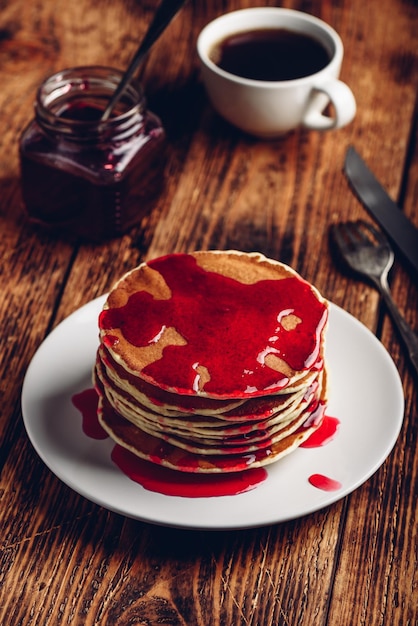 Stack of pancakes with berry fruit marmalade on plate over wooden surface