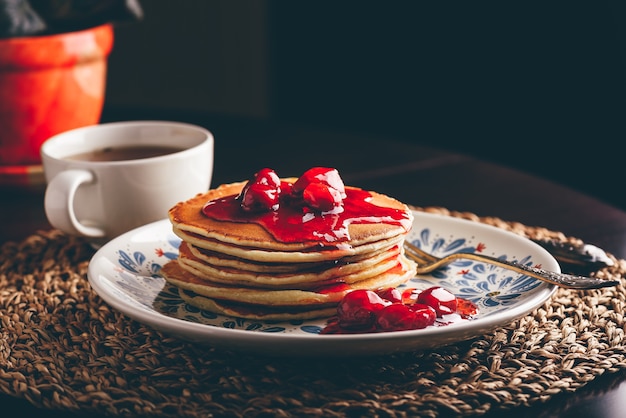 Stack of pancakes with dogwood berry marmalade on white plate with ornate