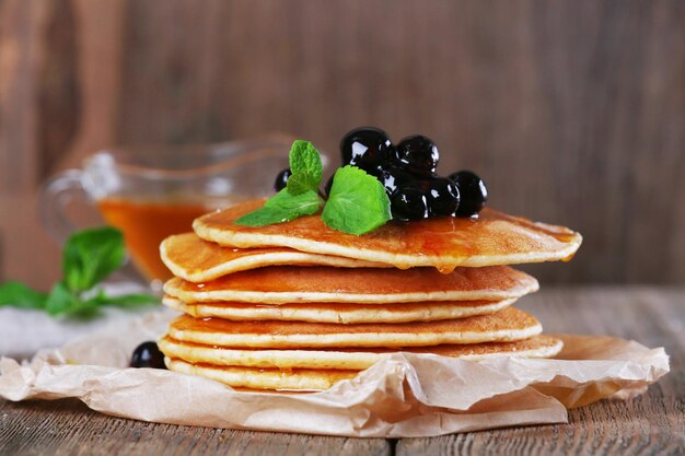 Stack of pancakes with mint and berries on rustic wooden background