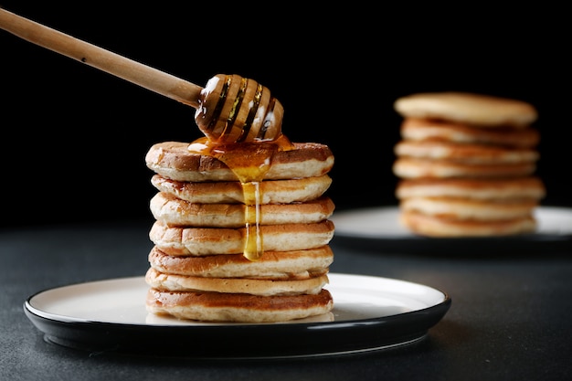 Stack of Pancakes with pouring honey on dark background. decoration and breakfast