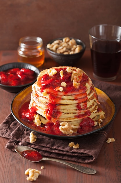 Stack of pancakes with strawberry jam and walnuts