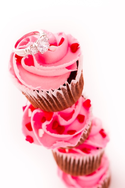 Stack of pink cupcakes with engagement ring on top.