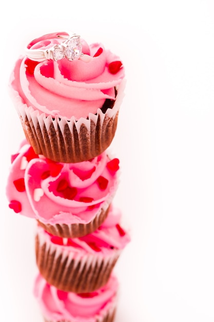 Stack of pink cupcakes with engagement ring on top.