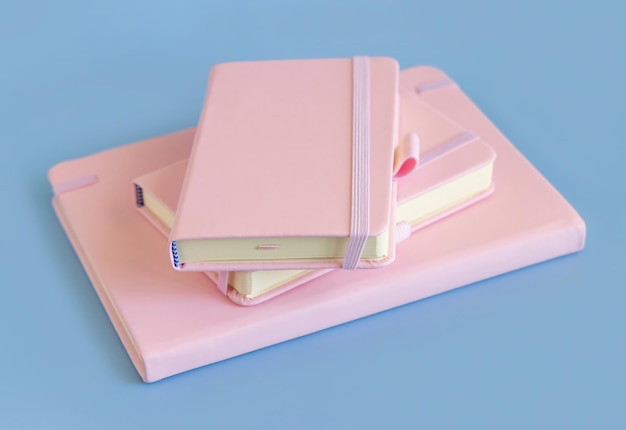 Stack of pink notebooks on light blue closeup. Textbook mockup. Educational, business and organizing concept