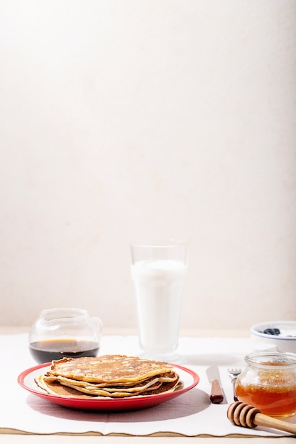 Stack of plain pancakes served with honey and blueberries