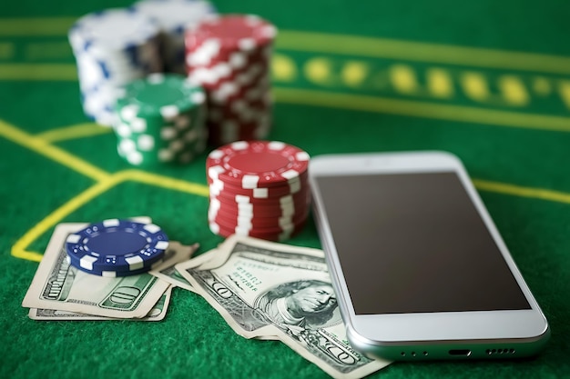 a stack of poker chips and a smartphone on a table with a pile of money