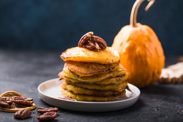 Stack of pumpkin pancakes with caramel sauce and pecan nuts