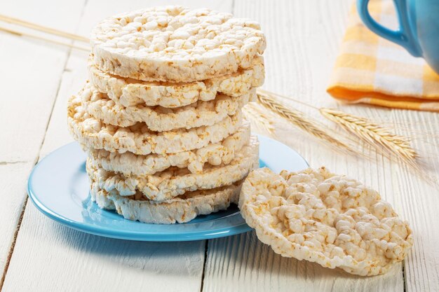 A stack of rice biscuits on a blue saucer and ears of barley on a wooden table