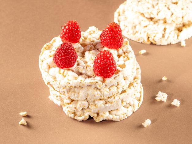 Stack of rice cakes with raspberries on top on beige background