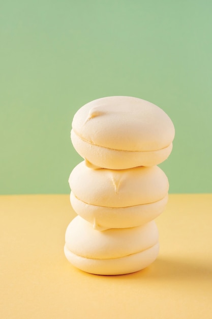 Stack of round yellow marshmallows on bicolor pastel background green and yellow closeup