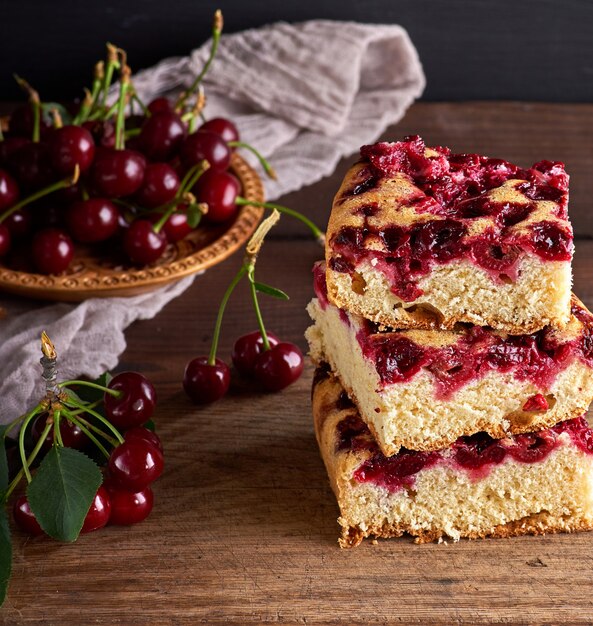 Stack of square slices of a baked pie with cherry berries 