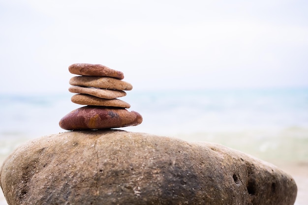 Stack Stone on sea at coast balance and harmony pebble tower pyramid on big rock with blur wave and blue ocean calm meditate or aroma vacation relax therapy spa nature wellness symbols concept