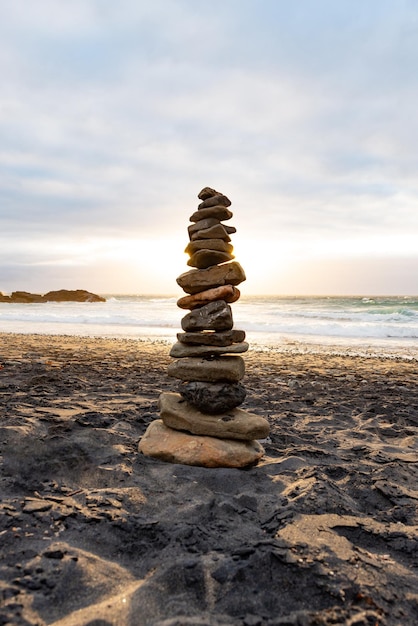 Stack of Stones Balance on a Beach Against a Cloudy Sky at Sunset TimeZen ConceptVertical Image