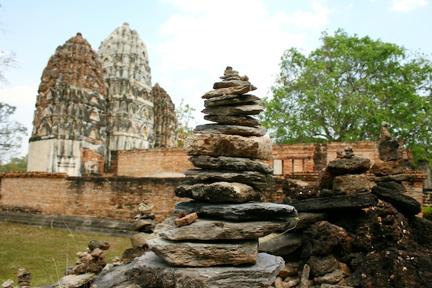 A stack of stones in front of a temple with a large building in the background.