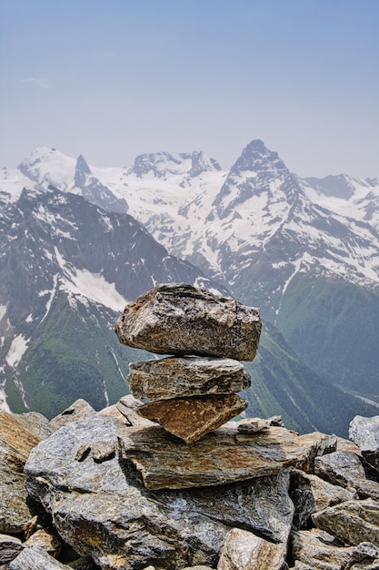 Stack of stones on top of the mountain against of mountain snow peaks