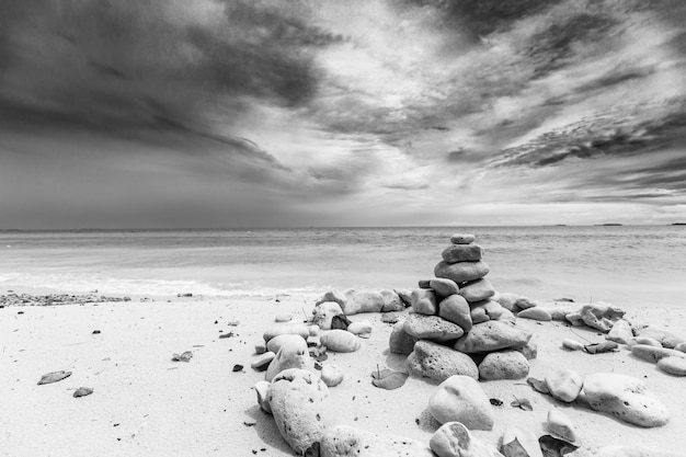 Stack of stones, Zen concept, on sandy beach. Stack of pebbles on sandy sea beach against dark sky