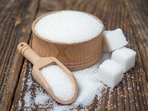 Stack of sugar cubes and granulated sugar in a wooden scoop