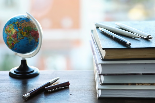 A stack of textbooks on the windowsill and writing utensils