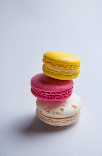 A stack of three delicious macaron and pink, white and yellow on a gray background