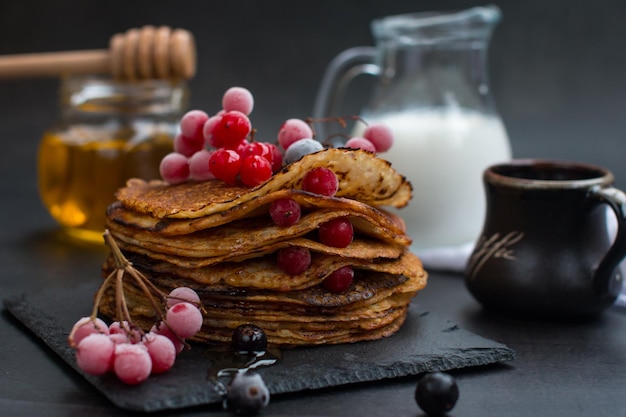 Stack of traditional Russian pancakes with honey on black background with Homemade Russian thin pancakes Russian national cuisine