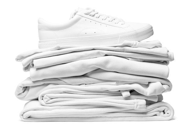 Stack of white clothes and stylish trainers isolated on white background