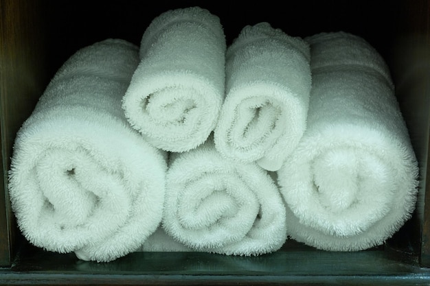 Stack of White Towel in Wooden Shelf on the Table