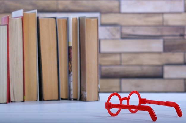 Stack with books and red glasses on the table education concept background