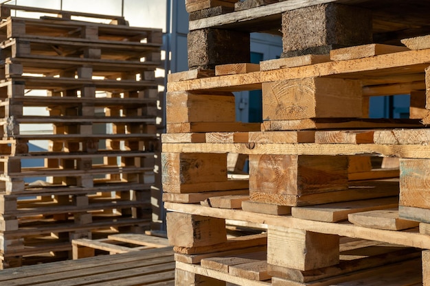 A stack of wooden pallets in an internal warehouse An outdoor pallet storage area under the roof next to the store Piles of Eurotype cargo pallets at a waste recycling facility