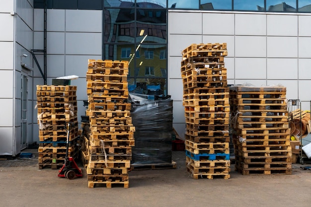 A stack of wooden pallets in an internal warehouse An outdoor pallet storage area under the roof next to the store Piles of Eurotype cargo pallets at a waste recycling facility