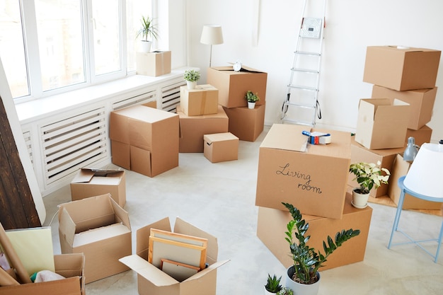 stacked cardboard boxes in empty room, moving, relocation and house decor concept