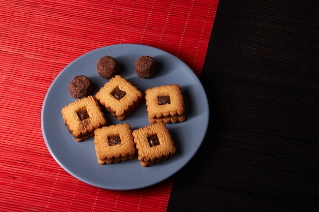 Stacked chocolate chip cookies on gray style plate on red and black wooden table