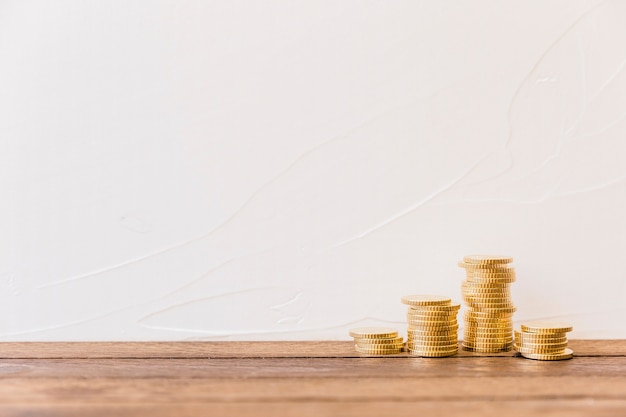 Stacked golden coins in front of wall