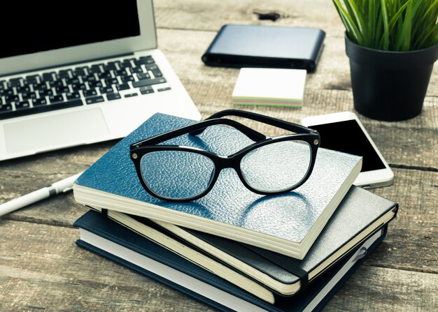 Stacked notepads on office table with eyeglasses