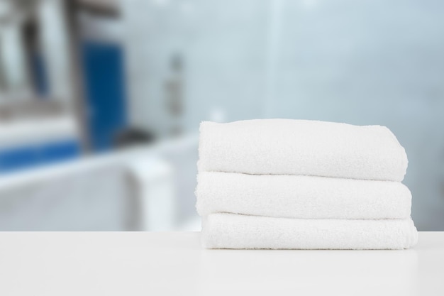 Stacked white spa towels on table against blurred background