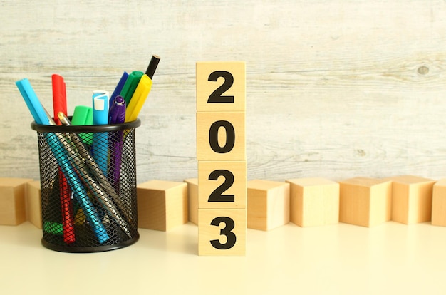 Stacked wooden cubes with letters 2023 on a white work table on a textured gray background