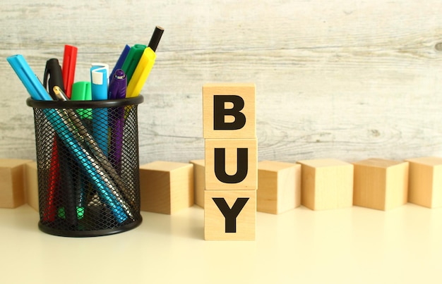 Stacked wooden cubes with letters buy on a white work table on a textured gray background